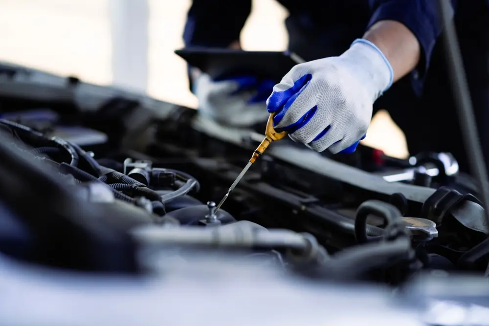 Auto repair technician inspecting fluid levels during preventive maintenance