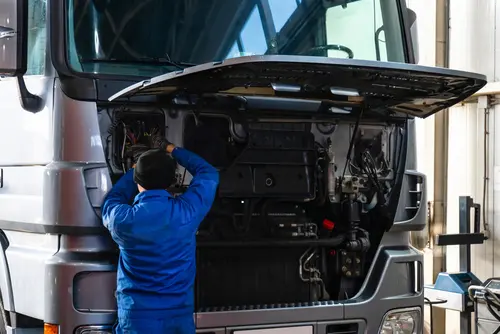 Mechanic performing service on a pickup truck engine bay