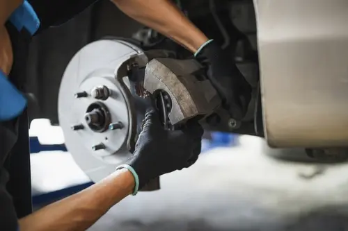 Mechanic replacing brake pads and inspecting rotors